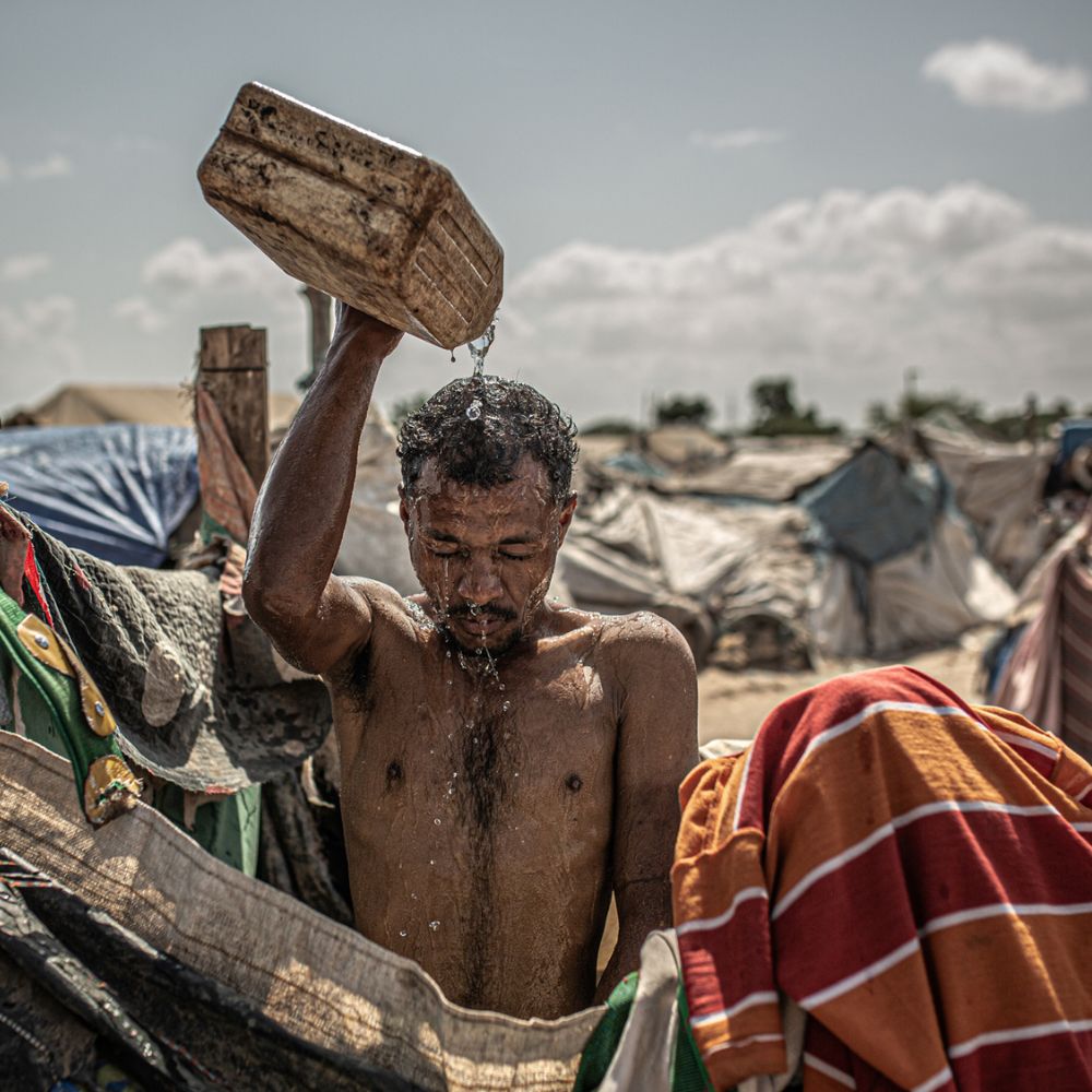 Mand hælder vand fra dunk over sig