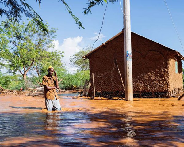 Mand står i vand til knæene i oversvømmet landsby