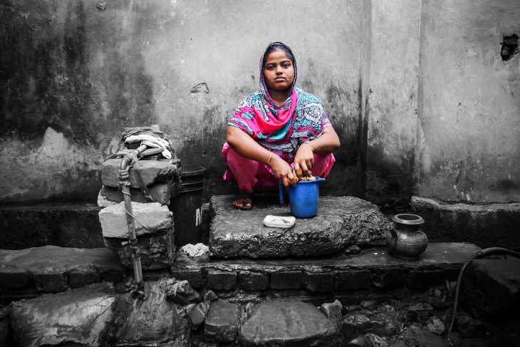 Kvinde i farvestrålende dragt foran grå mur