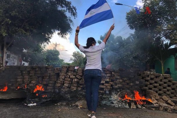 En kvindelig demonstrant nær en brændende barrikade. Det er Nicaraguas unge, der leder an i protesterne