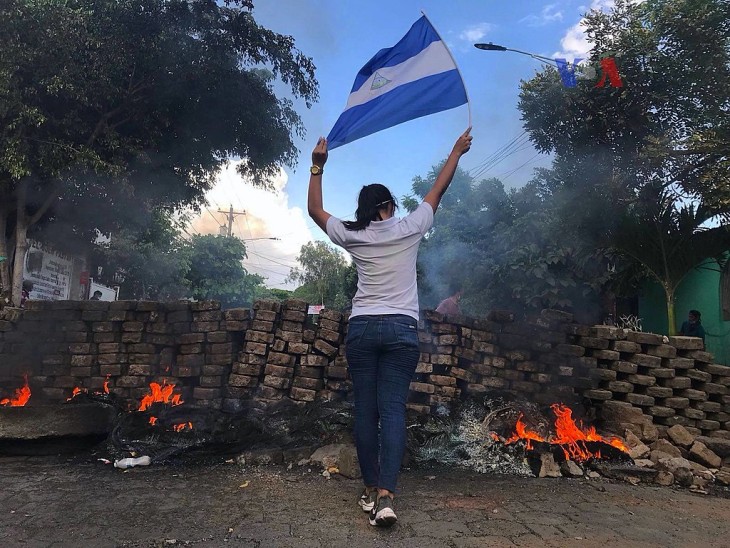 En kvindelig demonstrant nær en brændende barrikade. Det er Nicaraguas unge, der leder an i protesterne