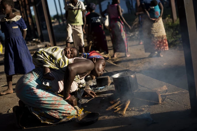 Kvinde laver mad over bål. Bangula-campen, Malawi.