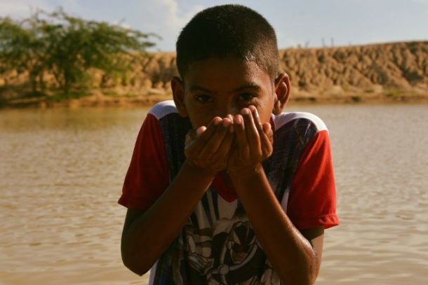 Dreng drikker vand fra reservoir, Colombia