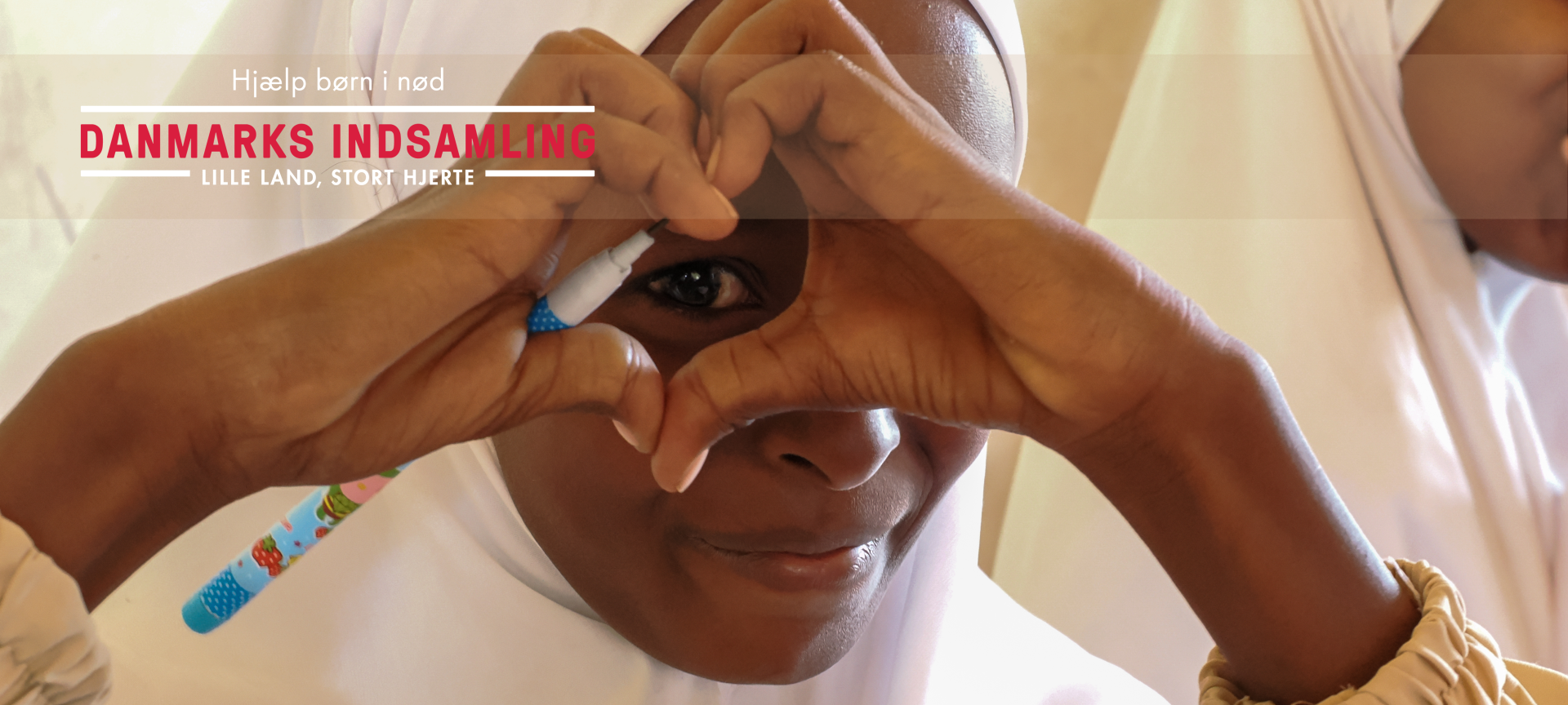 Barn laver hjertetegn med hænderne