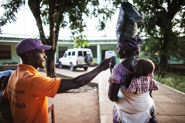 En kvinde får taget temperaturen inden hun går ind på hospitalet i Tombali