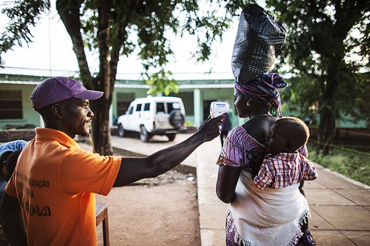 En kvinde får taget temperaturen inden hun går ind på hospitalet i Tombali