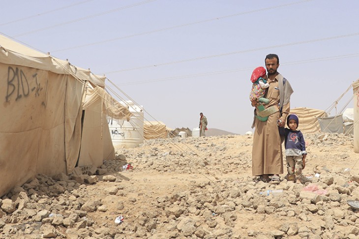 Mand med to børn foran telt i lejr i ørken - fødevarerkrise