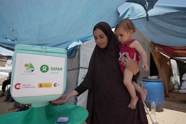 Kvinde med barn ved håndvaskestation, Gaza 2024