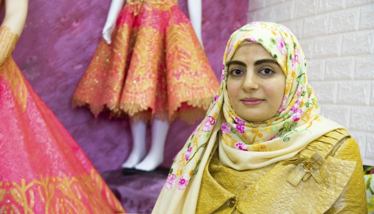 Kvinde med blomstret tørklæde, dukker i baggrunden