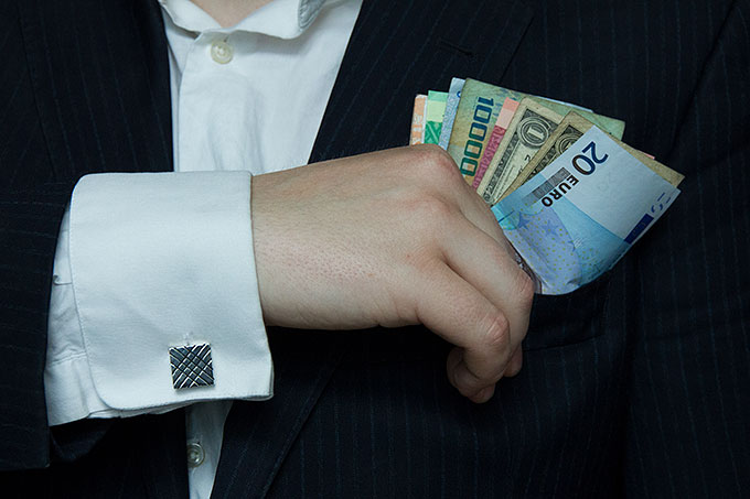 Skattely: Hånd med pengesedler i varierende valuta