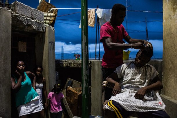 Mand klipper hår på en anden mand i skumringen - Haiti